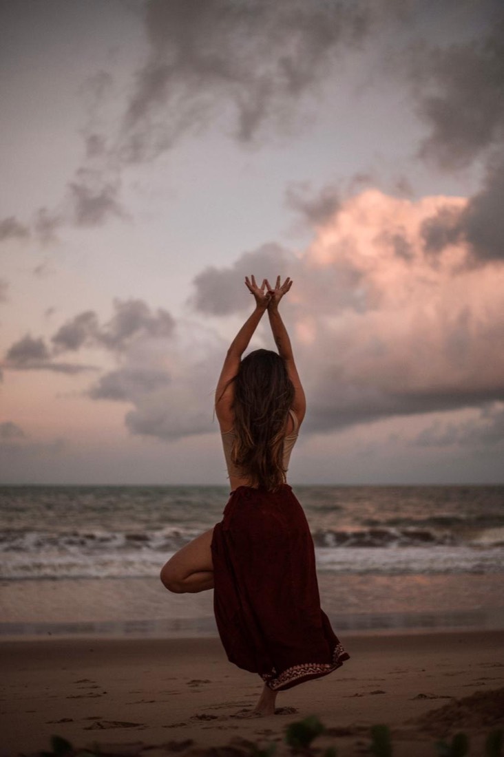 Madu em postura da árvore voltada para o mar ao entardecer
