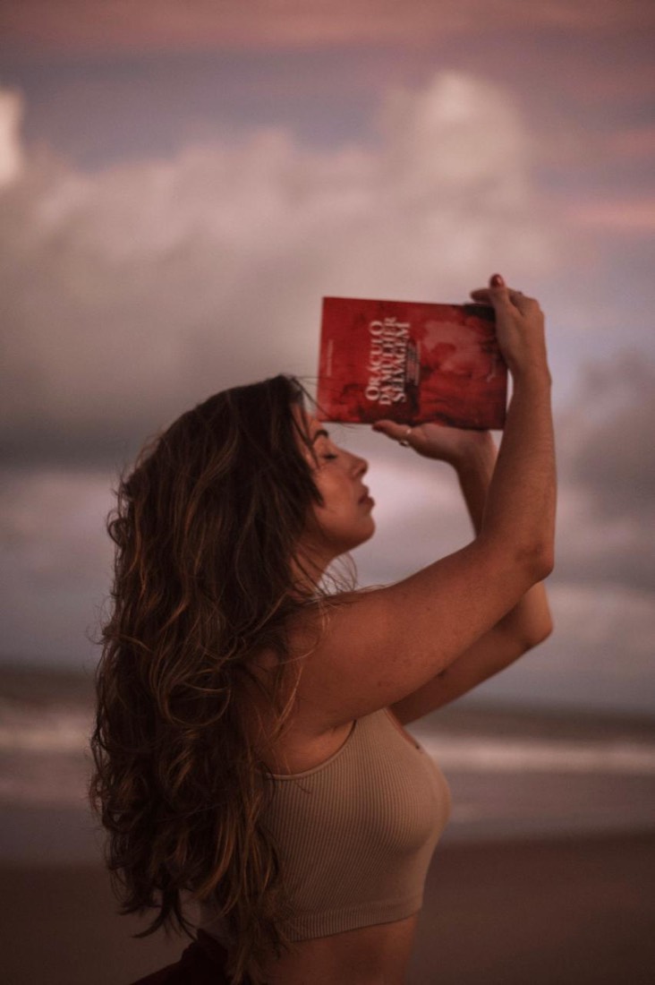 Madu levando o oráculo à testa, de perfil diante do mar