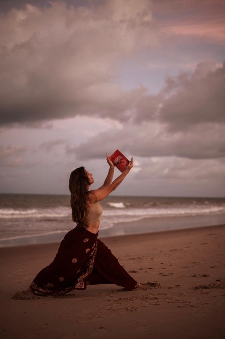 Madu ajoelhada erguendo o oráculo ao céu na praia